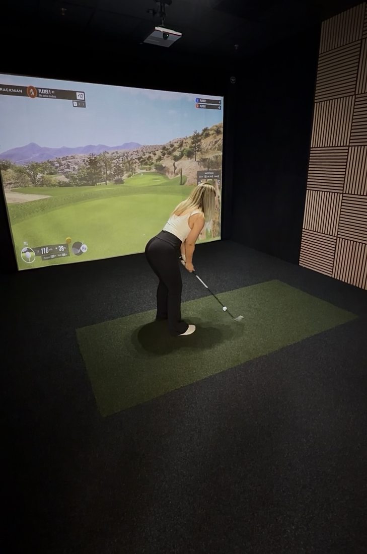 Golfer taking a swing in the TrackMan simulator bay at Impact Performance